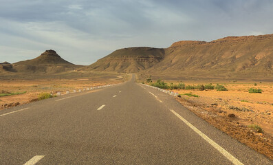 Long road through the Moroccan desert along the Atlas Mountains