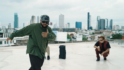 Obraz premium Professional break dance team practice B-boy dance while multicultural friends at rooftop. Young modern dancing group doing hip hop movement. Style,fashion,action. Outdoor sport 2024. Hiphop.