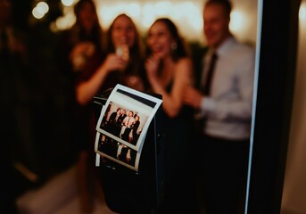 Instant photos printing from a photo booth at a party with blurred guests celebrating in the background
