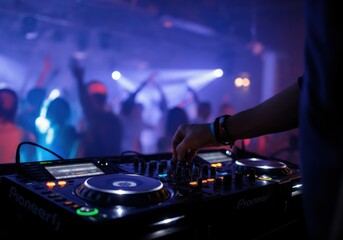 Dj mixing music on a console in a nightclub with blurred people dancing in the background