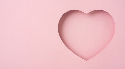 A minimalist heart shaped cutout on a pastel pink paper background, evoking feelings of love and...