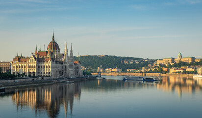 Fototapeta premium Morning panorama of Budapest with the Hungarian Parliament Building, the Danube River, and the Buda Castle in the distance, creating a serene and picturesque scene.
