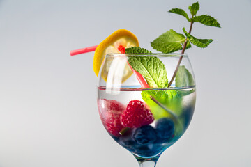 cocktail berry raspberry blueberry lemon and mint in a glass with a straw