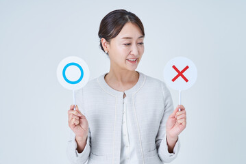 マルとバツのプレートを持つビジネスウーマン