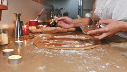 Person preparing festive holiday cookies with warm candle ambiance