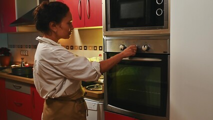 Woman adjusting oven temperature in a modern kitchen setting
