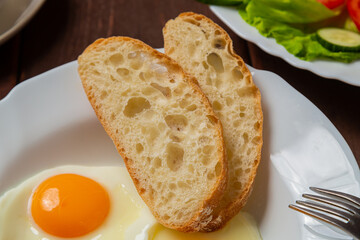 Breakfast fried eggs with sausages, crispy white bread, on a wooden table