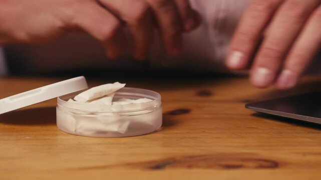 Snus nicotine tobacco close up, pack of tobacco for gum. unhealthy addiction. Man opening box with snus and taking one. 