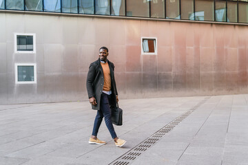 Young african businessman walking outside office building