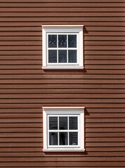 Two floors of windows on a red wooden facade