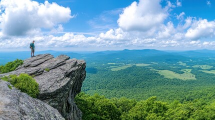 Fototapeta premium Hiker Stands on a Mountaintop Overlooking a Vast Green Valley