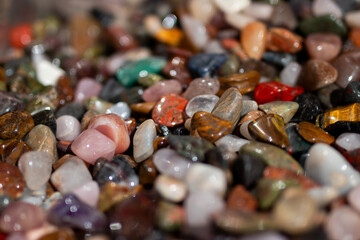 A close-up of colorful polished gemstones, including quartz, tiger's eye, and agate, with a vibrant...