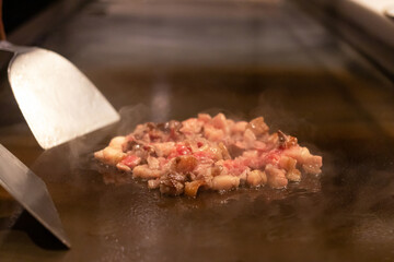 Sizzling meat cooking on a hot grill surface.