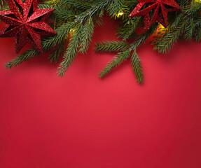 Christmas decorated fir tree branch top view on red empty space background, holiday lights and decorations. Border, frame