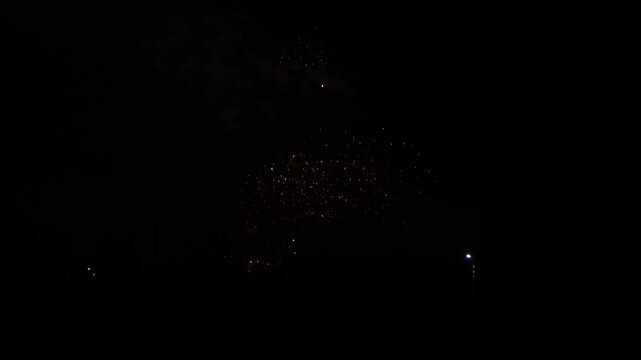 red and gold sparks scatter fireworks on the black night sky above the city. General plan