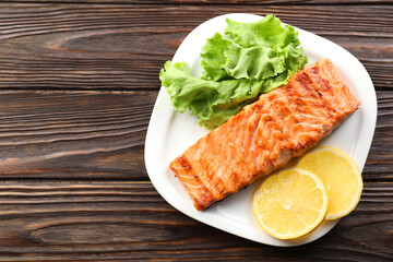 Delicious grilled salmon fillet served on wooden table, top view
