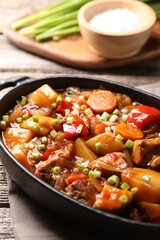 Delicious stew with vegetables in baking dish on wooden table, closeup