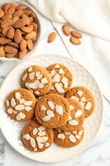 Tasty cookies with almond flakes and nuts on white marble table, top view