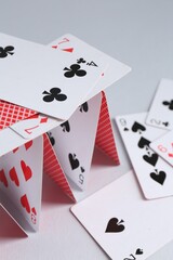 Collapsed house of playing cards on light grey background, closeup