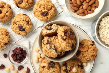 Delicious oatmeal cookies with raisins and nuts on white marble table, flat lay
