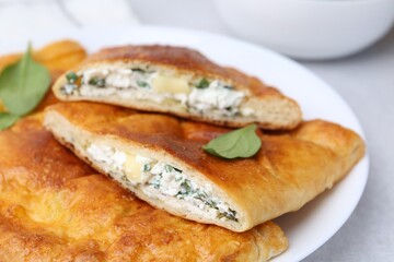 Tasty calzones with cheese and basil on table, closeup