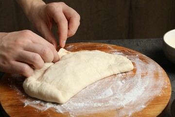 Woman making calzone pizza at grey table, closeup