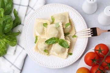 Delicious ravioli with cheese and basil served on light table, flat lay