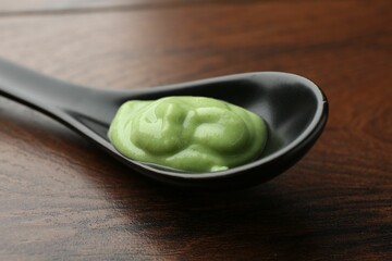 Spoon with hot wasabi paste on wooden table, closeup