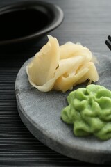 Hot wasabi paste, soy sauce and ginger on black textured table, closeup