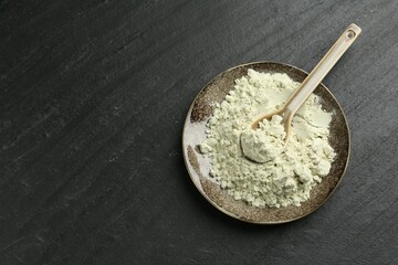 Plate with dry wasabi powder and spoon on dark textured table, top view. Space for text