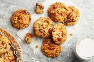 Tasty cookies with nuts and milk on grey table, flat lay