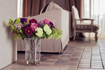 Close-up of a glass Vase with artificial flowers on the floor in a living room