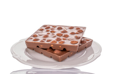 Two bars of dark chocolate with hazelnuts in a ceramic dish, close-up, isolated on a white background.