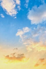 A bright sky at sunrise or sunset, with soft gradients of blue mixed with gold and orange, as clouds spread out, some illuminated by sunlight.