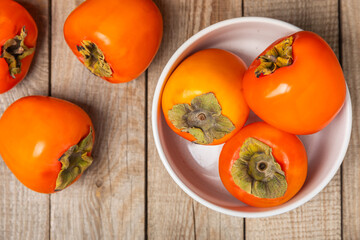 Persimmon on textured wooden background. Persimmon fruit. A piece of ripe, juicy, sweet persimmon fruit. Vegan. Orchard. Close-up. Space for text. Copy space.