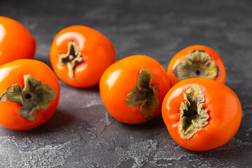 Persimmon on textured wooden background. Persimmon fruit. A piece of ripe, juicy, sweet persimmon fruit. Vegan. Orchard. Close-up. Space for text. Copy space.