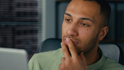 African american man manager looking at laptop screen writing financial report analyzing data from internet young ethnic businessman write notes doing paperwork in office workplace making presentation