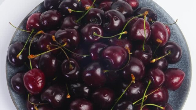 Scattering of ripe dark red cherries with branches rotating in a circle. Medium plan