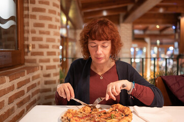 Redhead woman enjoying pizza in italian restaurant