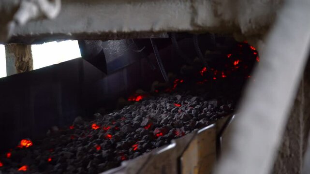 A cement factory featuring a conveyor transporting fired hot stones and gravel through a tunnel on the conveyor system.