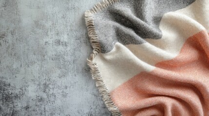 Soft, textured throw blanket in muted tones on a stone surface.