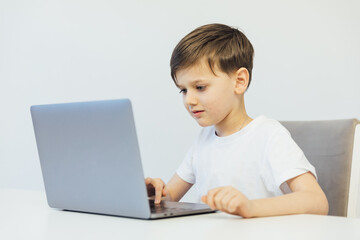 Little boy learning to play on laptop online at table