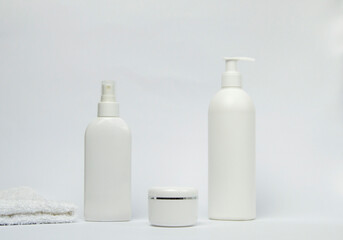 Set of white cosmetic bottles mockup with a towel on white background.