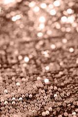 Beautiful Christmas light background. Abstract bokeh and scattered sequins in gold color of the year 2025 mocha mousse