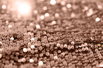 Beautiful Christmas light background. Abstract glitter bokeh and scattered sequins in gold color of the year 2025 mocha mousse