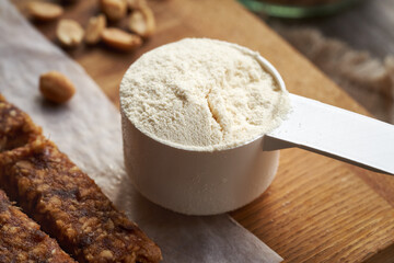 A scoop of whey protein powder with homemade no-bake healthy bars and peanuts