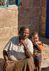 african child and granny, village in Botswana , sitting on the porch, in front of the house , sunny day, informal settlement