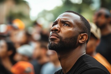 Man gazes upward, crowd blurred background.
