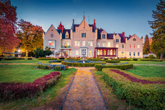 Green lawn at the front of Festetics Castle - Szombathely Home for the Elderly. Illuminated autumn cityscape of Szombathely town, Hungary, Europe. Amazing sunset in Hungarian countryside.