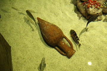 Amphora on the sand in the water. An ancient jug in an aquarium. Fossil
